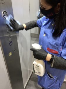 Trabajadora de Limpiezas Salym desinfectando botones de ascensor en comunidad de vecinos.