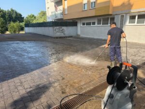 Trabajador realizando una limpieza con hidrolimpiadora en una plaza exterior